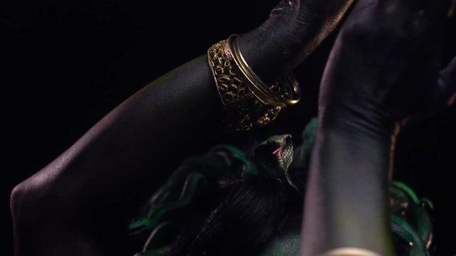 Woman with make up and body art, as Medusa Gorgon, moving her hands above her head