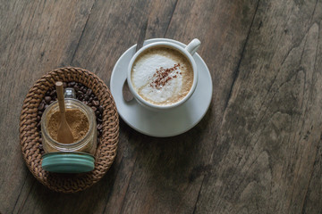 A cup of coffee in the wooden table.