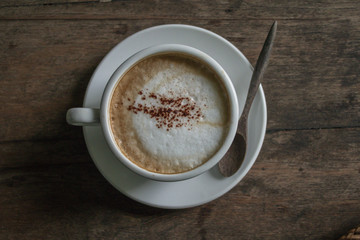 A cup of hot coffee in the wooden table dark tone background.