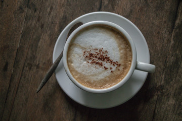 A cup of coffee in the wooden table.