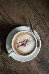A cup of hot coffee in the wooden table dark tone background.