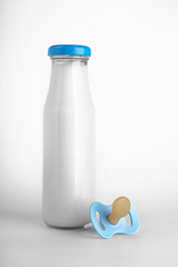 Bottle of milk for baby and and pacifier on white background