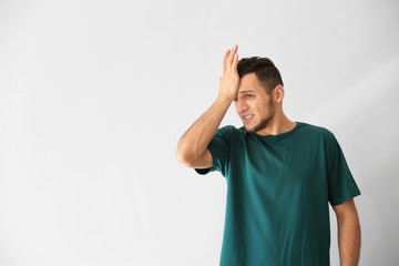 Emotional young man after making mistake on white background