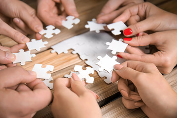 Group of people doing puzzle on table