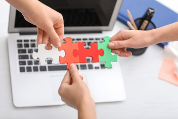 People with pieces of jigsaw puzzle in office