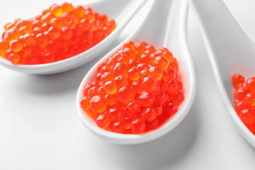 Spoons with delicious red caviar on white background, closeup