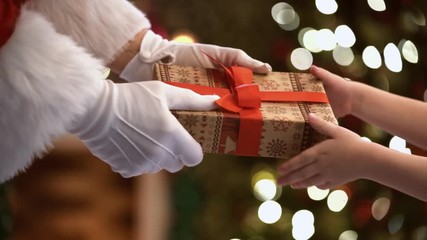 Merry Christmas and Happy Holidays! Hands of Santa Claus giving a x-mas gift to child.
- Powered by Adobe