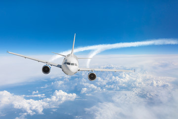 Passenger airplane flying at flight level high in the sky above the clouds and blue sky sunrise.