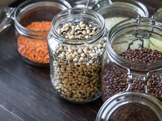 Open glass jars with pasta, lentils, couscous, beans and quinoa.