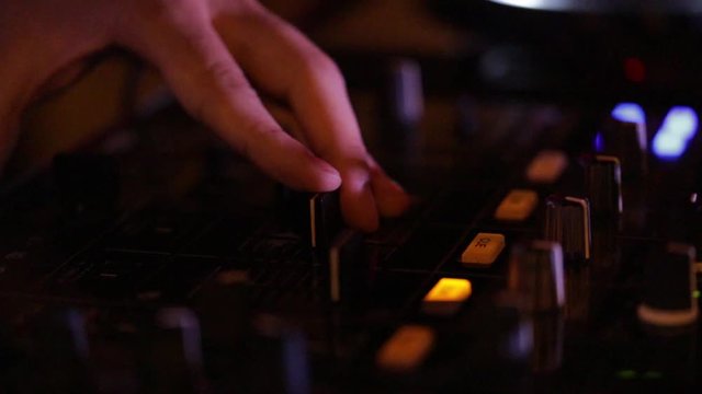 Deejay sta lavorando alla sua consolle mettendo musica per la folla che balla in un locale notturno