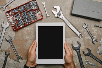 cropped view of laborer using digital tablet on table with different carpentry tools