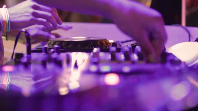 Deejay sta lavorando alla sua consolle mettendo musica per la folla che balla in un locale notturno