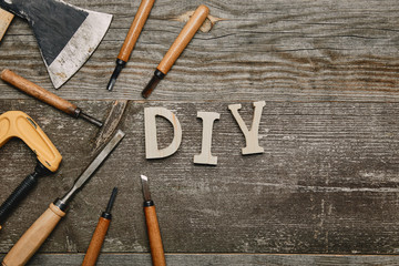 Top view of different carpentry tools and diy sign on wooden background