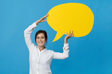 Businesswoman wearing white shirt holding blank speech bubble against blue background