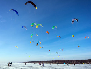 Kitesurfing in the winter on snowboard or ski. Skating on the ice in the wind. Beautiful colored sails.