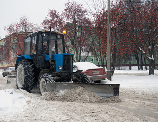 Blue tractor cleaning the streets of large amounts of snow in city after snowfall. A snowplow...