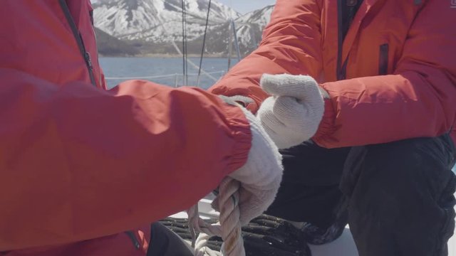 Male hands of sailor man tying sea knots on ropes on board sailing yacht