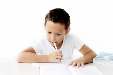boy schoolboy teaches lessons writing in notebook and reading books nibbling pen on white isolated background