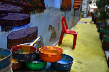 Paints and brushes (in focus) for anyone who wants to express their art (man painting in the background, out of focus)