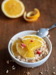Warmes Porridge Frühstück mit Orangen in einer weißen Schüssel, rustikaler Hintergrund