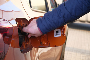 Man unscrews fuel filler cap in car. Fueling car with petrol pump at gas station. Petrol station....