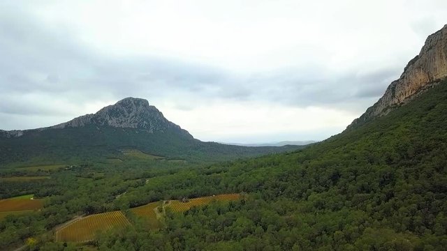 Aerial Drone Footage View: Flight between cloudy mountains with forests. Pic Saint Loup, Hortus, France, Europe. Majestic landscape. 4K resolution.