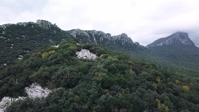 Aerial Drone Footage View: Flight between cloudy mountains with forests. Pic Saint Loup, Hortus, France, Europe. Majestic landscape. 4K resolution.