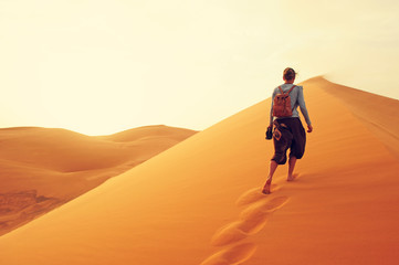 Sand dunes in the Sahara desert. Girl  between sand dunes. Landscape at Sunrise. Morocco, Africa.