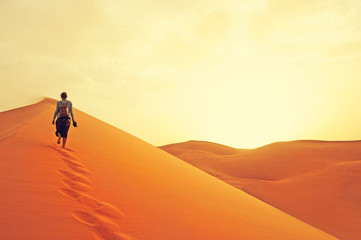 Sand dunes in the Sahara desert. Girl  between sand dunes. Landscape at Sunrise. Morocco, Africa.