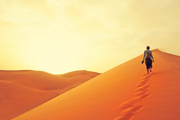 Fototapeta na wymiar Sand dunes in the Sahara desert. Girl between sand dunes. Landscape at Sunrise. Morocco, Africa.