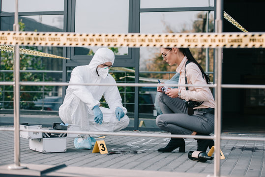 feamale detective and male criminologist inspecting the crime scene