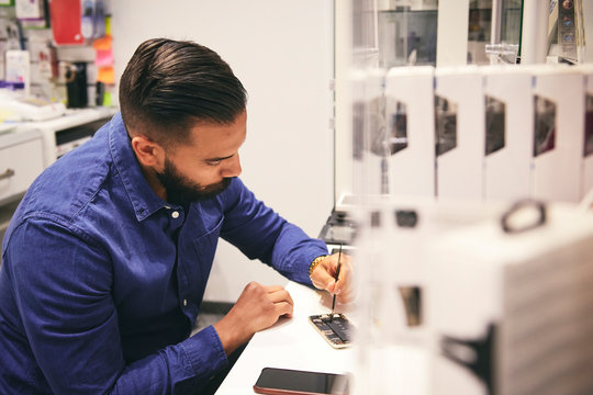 Technician repairing mobile phone at table in workshop