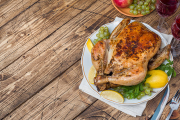 Baked chicken, wine glasses and fruit for dinner on the festive table. copy space