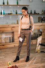 serious female detective investigating evidence at crime scene