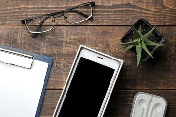 Smartphone white and a cup with coffee glasses and a blank on a brown wooden table. view from above