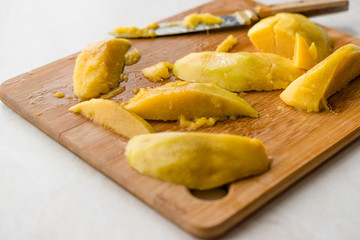 Mango Fruit with Slices Cut with Knife on Wooden Surface Board.