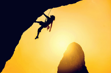 Silhouette of man climbing at sunset. Climber climb on the rock.