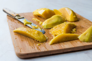 Mango Fruit with Slices Cut with Knife on Wooden Surface Board.