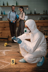 concentarted forensic investigator examining evidence with magnifying glass at crime scene with...