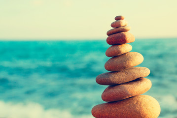 Abstract background. Stone tower on a pebble beach on a background of blue sky and sea. Concept of balance and harmony