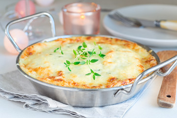 Cheesy scalloped potatoes or potato gratin in baking dish, holiday theme, horizontal