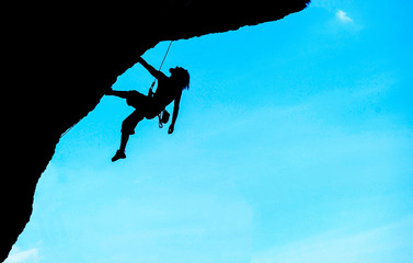 Silhouette of man climbing at sunset. The rock climber during ro