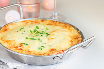 Cheesy scalloped potatoes or potato gratin in a baking dish, holiday theme, horizontal, copy space