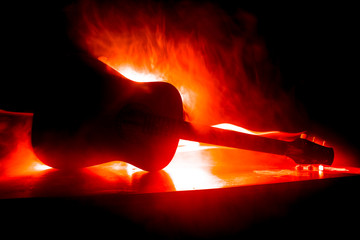 Music concept. Acoustic guitar isolated on a dark background under beam of light with smoke with...