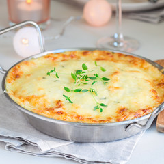 Cheesy scalloped potatoes or potato gratin in baking dish, holiday theme, square format