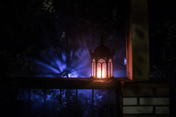 Fototapeta premium Retro style lantern at night. Beautiful colorful illuminated lamp at the balcony in the garden. Selective focus