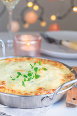 Cheesy scalloped potatoes or potato gratin in baking dish, holiday theme, vertical