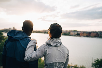 Rear view of athletes looking at sea while standing on hill