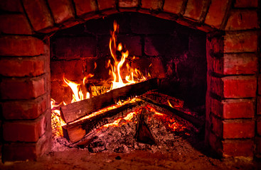 Autumn or winter burning fireplace cozy evening concept close up. Close up shot of burning firewood in the fireplace.