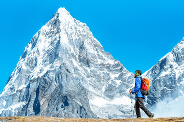 Hiker with backpacks reaches the summit of mountain peak. Success, freedom and happiness, achievement in mountains. Active sport concept.